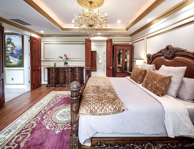 bedroom with a chandelier, dark hardwood / wood-style flooring, crown molding, and a tray ceiling