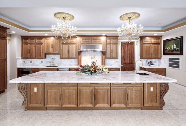 kitchen with a tray ceiling, a large island, sink, and hanging light fixtures