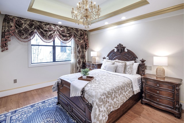 bedroom featuring a notable chandelier, a raised ceiling, light wood-type flooring, and crown molding