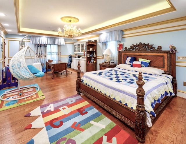 bedroom featuring hardwood / wood-style floors, a raised ceiling, ornamental molding, and a notable chandelier