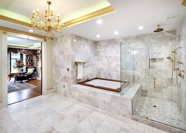 bathroom featuring separate shower and tub, a tray ceiling, a chandelier, and tile walls