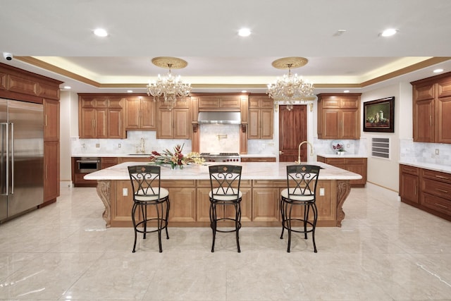 kitchen with appliances with stainless steel finishes, a tray ceiling, and a large island with sink