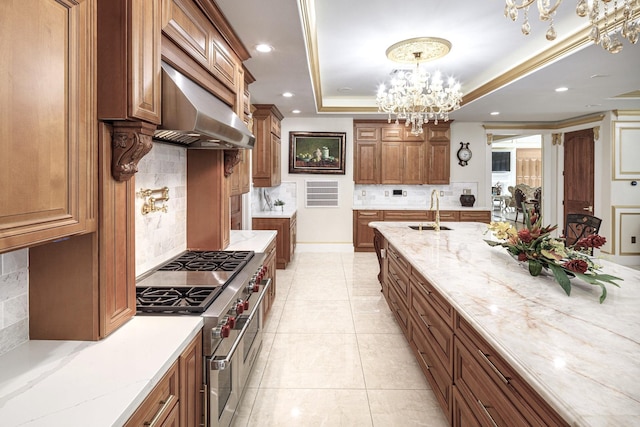 kitchen with backsplash, a raised ceiling, sink, range with two ovens, and an inviting chandelier