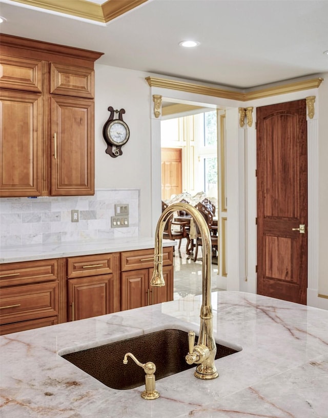 kitchen with light stone countertops, decorative backsplash, and sink