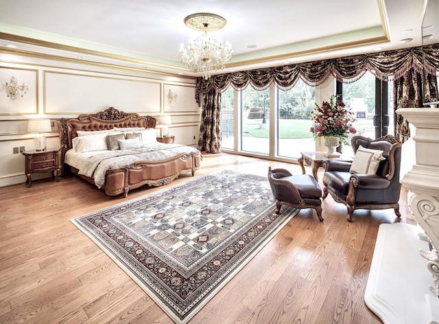 bedroom featuring a raised ceiling, light wood-type flooring, access to outside, and a chandelier