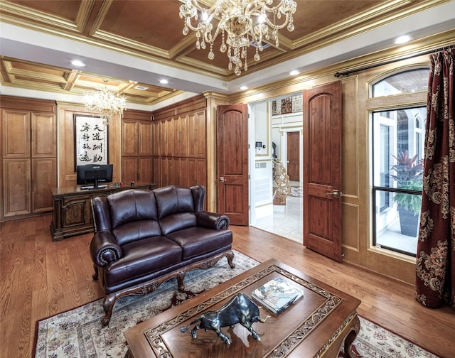 living room with an inviting chandelier, light wood-type flooring, coffered ceiling, and ornamental molding