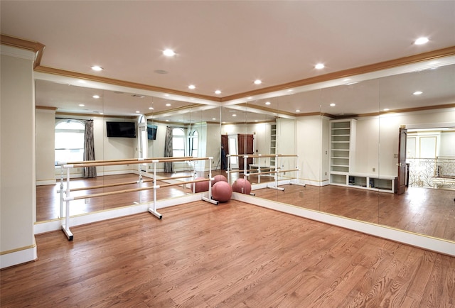 workout area with wood-type flooring and crown molding