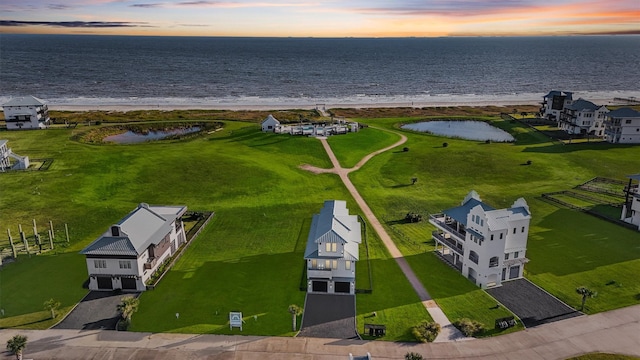 aerial view at dusk with a water view and a view of the beach