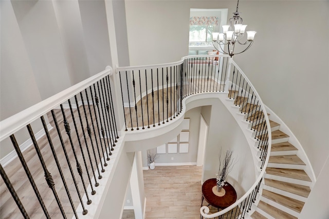 stairway with wood-type flooring and an inviting chandelier