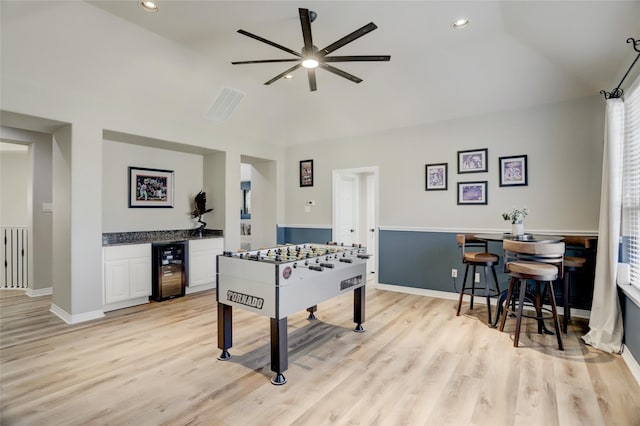 playroom with lofted ceiling, indoor bar, ceiling fan, light wood-type flooring, and beverage cooler