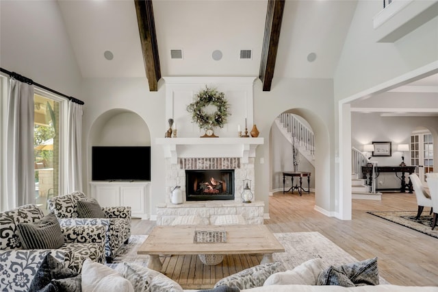 living room with a fireplace, light hardwood / wood-style flooring, high vaulted ceiling, and beamed ceiling