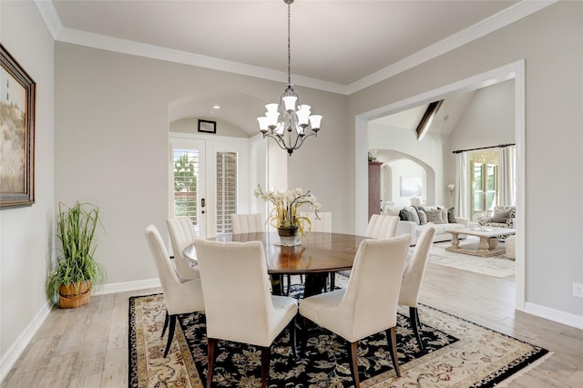 dining space featuring plenty of natural light, light wood-type flooring, ornamental molding, and vaulted ceiling