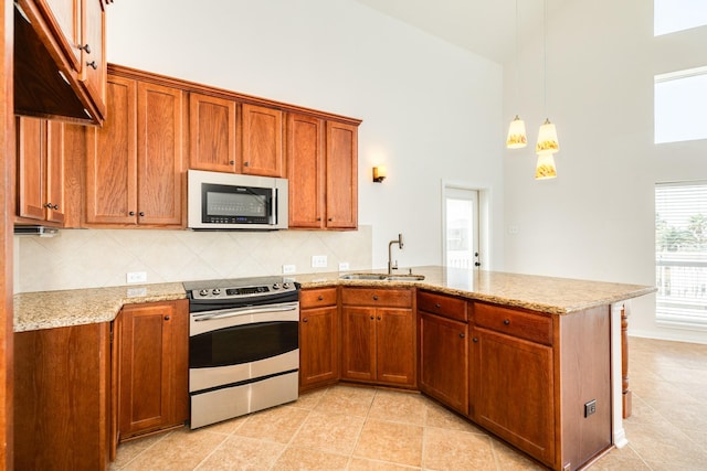 kitchen with decorative light fixtures, sink, appliances with stainless steel finishes, and a high ceiling