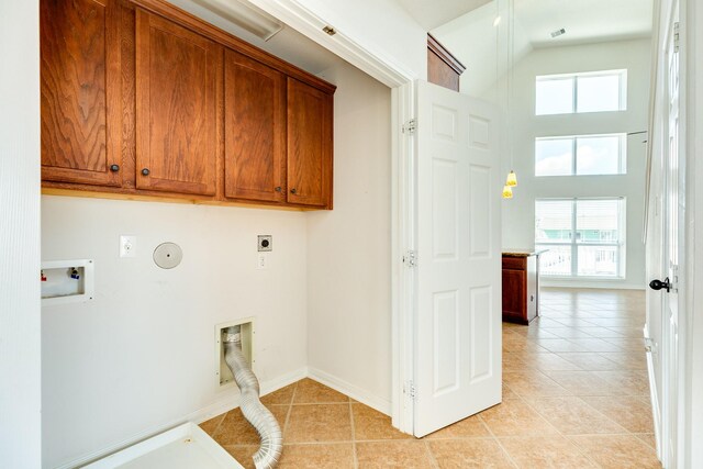 washroom featuring cabinets, plenty of natural light, hookup for an electric dryer, and light tile patterned flooring