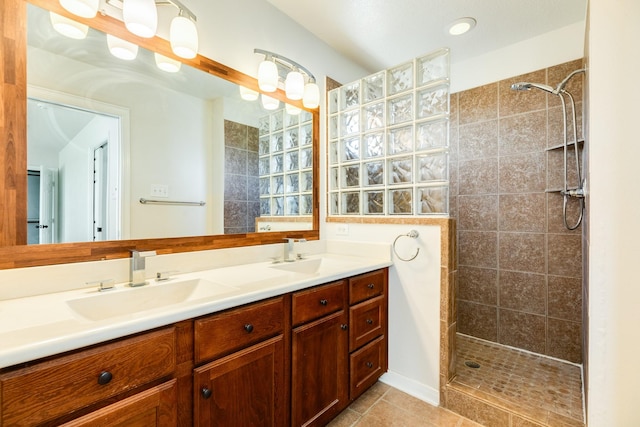 bathroom featuring tile patterned flooring, vanity, and tiled shower