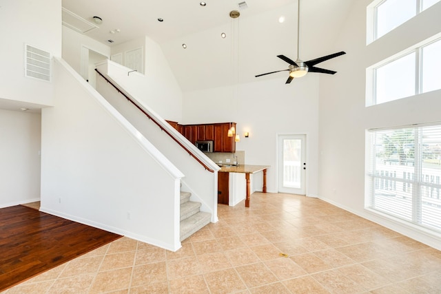 interior space with ceiling fan, high vaulted ceiling, and light hardwood / wood-style flooring