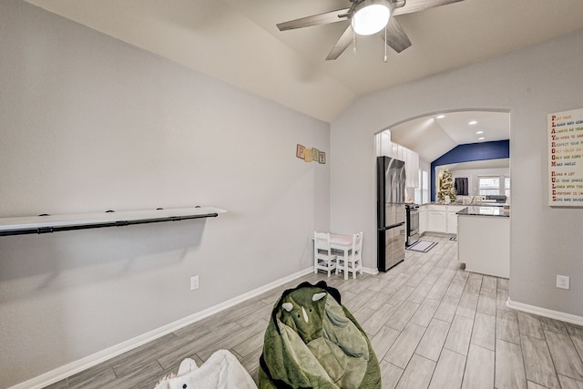 interior space featuring vaulted ceiling, white cabinetry, stainless steel appliances, light wood-type flooring, and ceiling fan