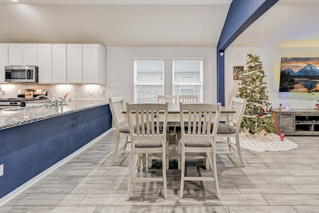 dining space with lofted ceiling with beams