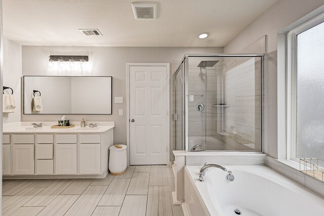 bathroom featuring vanity, independent shower and bath, and a healthy amount of sunlight