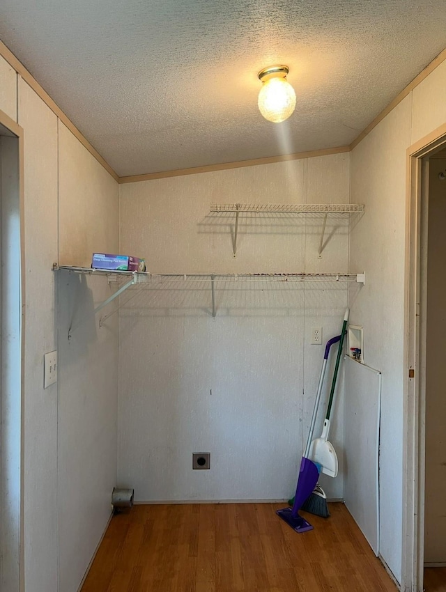 washroom with hookup for an electric dryer, hookup for a washing machine, a textured ceiling, hardwood / wood-style flooring, and ornamental molding