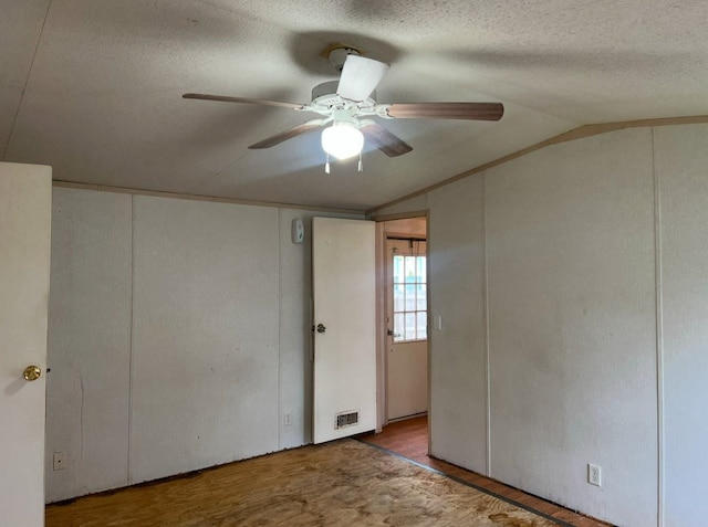 unfurnished room featuring hardwood / wood-style floors, ceiling fan, a textured ceiling, and vaulted ceiling