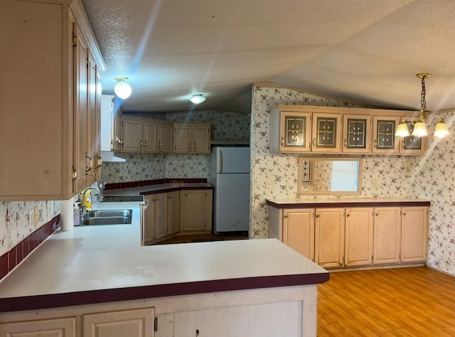 kitchen featuring kitchen peninsula, vaulted ceiling, white refrigerator, light hardwood / wood-style floors, and hanging light fixtures