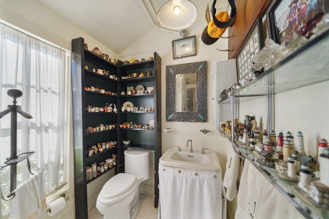 bathroom with tile patterned floors, vanity, toilet, and lofted ceiling