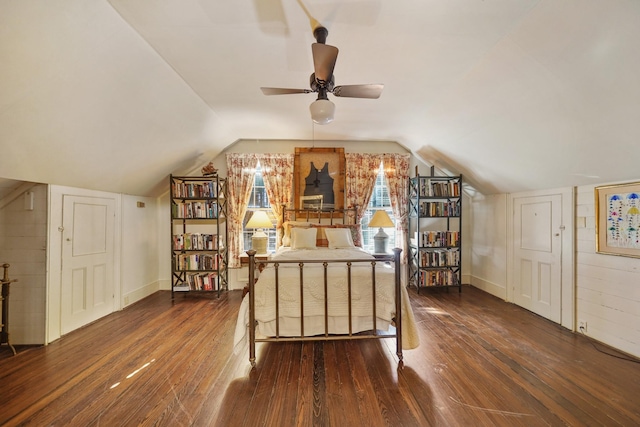 bedroom with lofted ceiling, wooden walls, and dark hardwood / wood-style floors