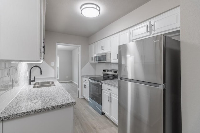 kitchen with sink, stainless steel appliances, tasteful backsplash, light hardwood / wood-style floors, and white cabinets