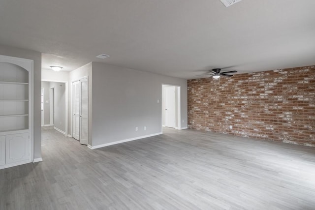 unfurnished living room featuring hardwood / wood-style floors, ceiling fan, built in features, and brick wall