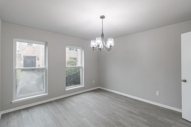 unfurnished room with hardwood / wood-style flooring and a notable chandelier