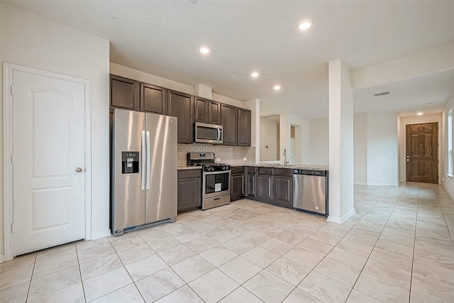 kitchen featuring backsplash, light stone counters, stainless steel appliances, sink, and light tile patterned floors