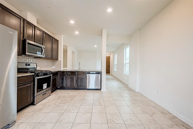 kitchen featuring appliances with stainless steel finishes, light tile patterned floors, dark brown cabinets, and sink