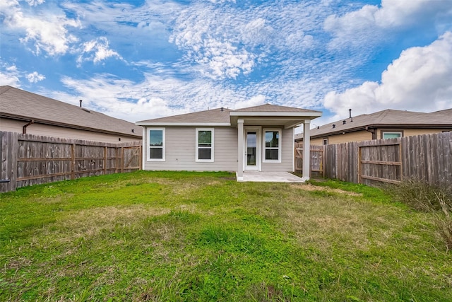 rear view of house featuring a lawn and a patio