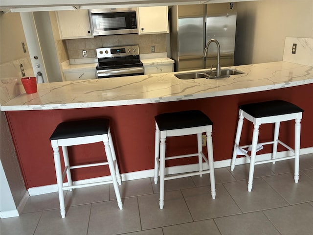 kitchen with sink, a kitchen bar, stainless steel appliances, and tasteful backsplash