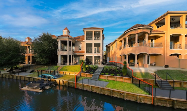 back of property featuring a patio area, a water view, and a yard