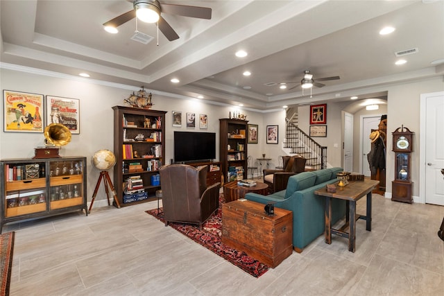 living room with a tray ceiling and ceiling fan