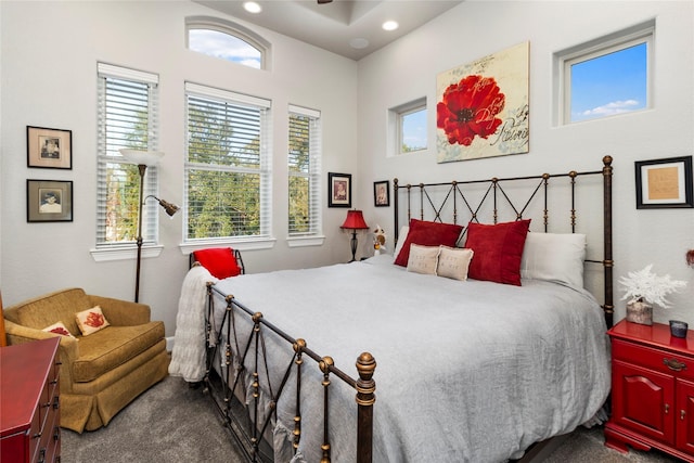 bedroom with dark colored carpet and multiple windows