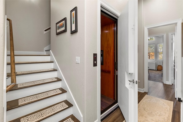 stairway featuring elevator and hardwood / wood-style flooring