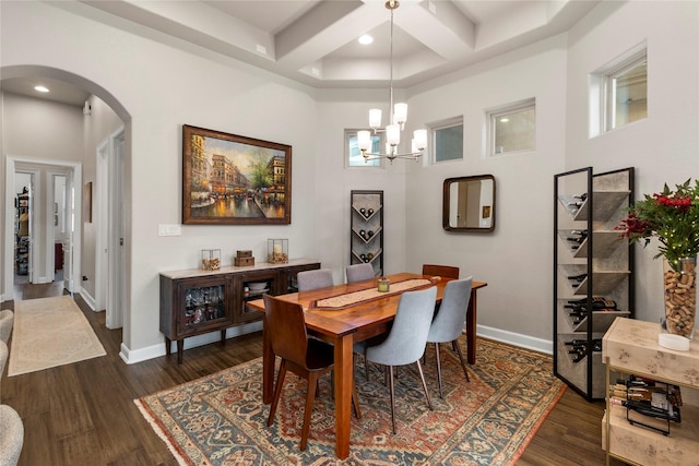 dining area featuring coffered ceiling, beam ceiling, an inviting chandelier, a high ceiling, and dark hardwood / wood-style floors