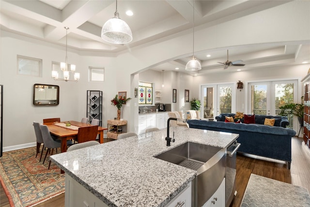 kitchen with a kitchen island with sink, coffered ceiling, french doors, decorative light fixtures, and dark hardwood / wood-style flooring