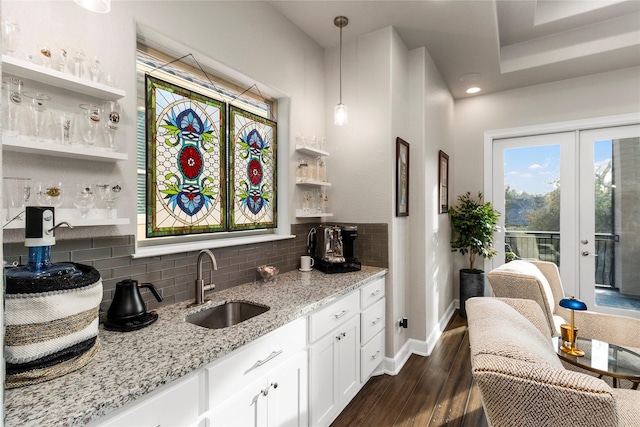 kitchen featuring white cabinets, sink, light stone countertops, decorative light fixtures, and dark hardwood / wood-style flooring