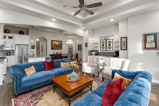 living room with ceiling fan with notable chandelier, light wood-type flooring, and sink