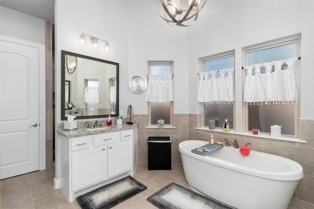 bathroom with tile patterned floors, a washtub, vanity, and tile walls