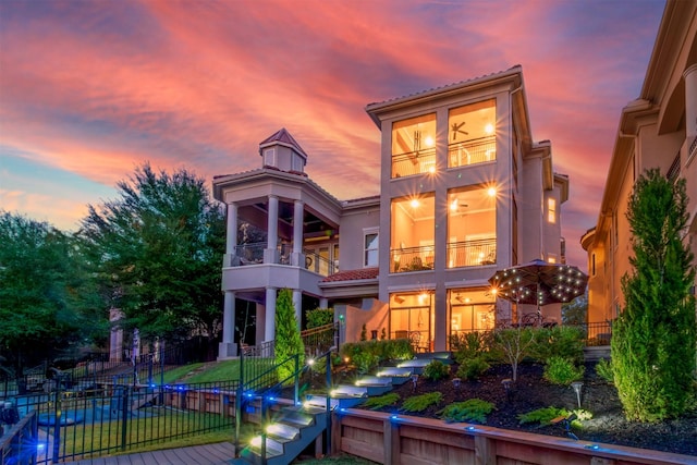 back house at dusk featuring a balcony