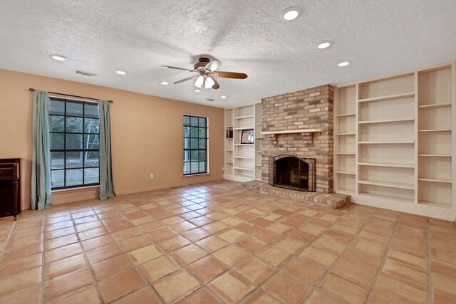 unfurnished living room featuring light tile patterned flooring, ceiling fan, a fireplace, and a textured ceiling