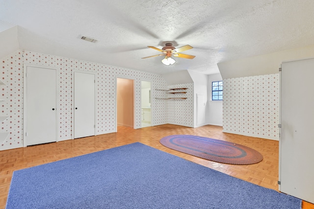 additional living space featuring ceiling fan, parquet floors, and a textured ceiling