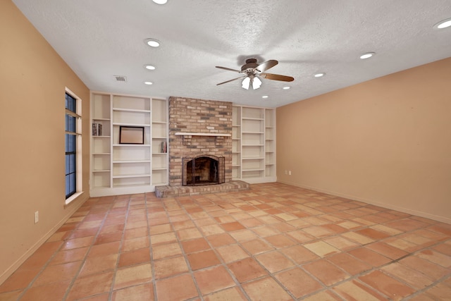 unfurnished living room featuring a brick fireplace, built in features, a textured ceiling, and ceiling fan