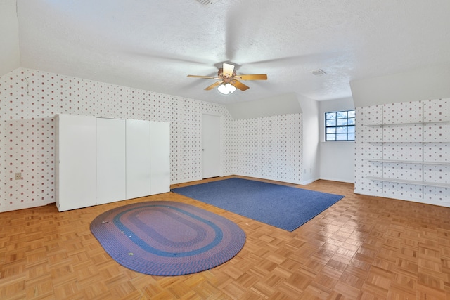 additional living space featuring ceiling fan, light parquet flooring, and a textured ceiling