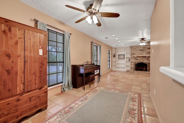 foyer with light tile patterned floors, ceiling fan, a textured ceiling, and a brick fireplace